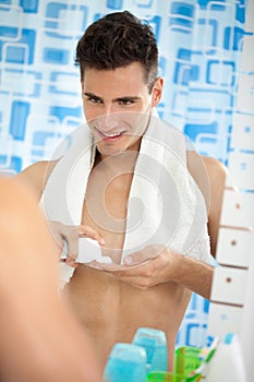 Young man in the bathroom's mirror with shave foam on hand