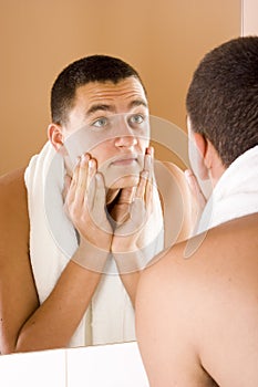 Young man in the bathroom's mirror after shaving