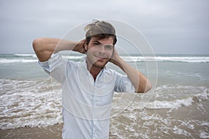 Young man on beach with arms behind head