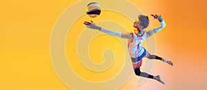 Young man, beach volleyball player in motion, training, servig ball in jump  over yellow studio background in