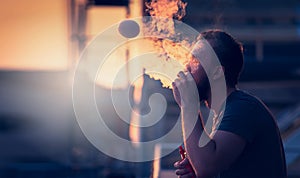 Young man with beard on blurry background sunset sky, making soap bubbles smoke inside with the aid of vape