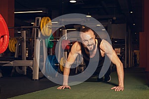 A young man with a beard does a push-up exercise in the gym