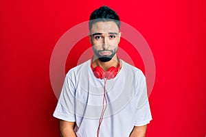 Young man with beard listening to music using headphones depressed and worry for distress, crying angry and afraid