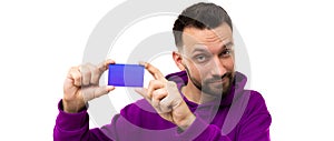 a young man with a beard in a purple sweatshirt demonstrates a business card in his hands on a white background