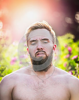 Young man with beard and straight face on sunset nature background, , close up