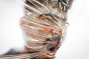 Young man with a beard suffocating with plastic around his head