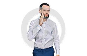 Young man with beard wearing business shirt touching mouth with hand with painful expression because of toothache or dental
