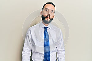 Young man with beard wearing business tie making fish face with lips, crazy and comical gesture