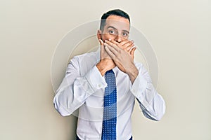 Young man with beard wearing business tie shocked covering mouth with hands for mistake