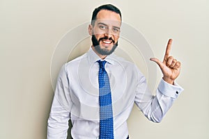 Young man with beard wearing business tie showing and pointing up with fingers number two while smiling confident and happy