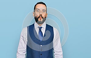 Young man with beard wearing business vest making fish face with lips, crazy and comical gesture