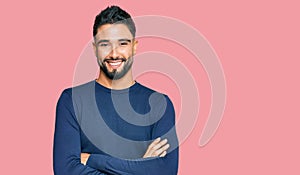 Young man with beard wearing casual blue winter sweater happy face smiling with crossed arms looking at the camera