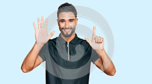Young man with beard wearing sportswear showing and pointing up with fingers number seven while smiling confident and happy