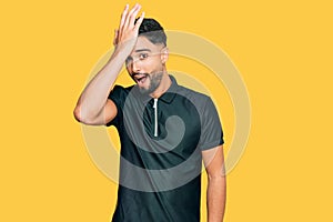 Young man with beard wearing sportswear surprised with hand on head for mistake, remember error