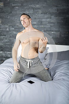 Young man in bed playing air guitar