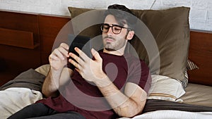 Young man on bed reading with ebook reader