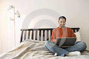 Young Man in Bed Using Laptop