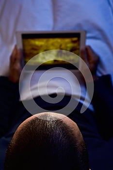 Young man in bed watching a movie or a series in his tablet