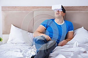 The young man in bed wearing a vr virtual reality head set