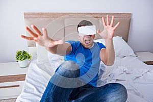 The young man in bed wearing a vr virtual reality head set