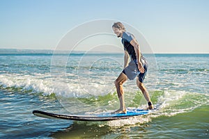 Young man, beginner Surfer learns to surf on a sea foam on the B