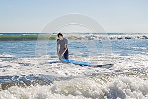 Young man, beginner Surfer learns to surf on a sea foam on the B