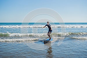 Young man, beginner Surfer learns to surf on a sea foam on the B