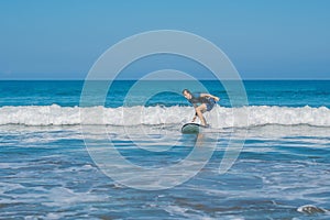 Young man, beginner Surfer learns to surf on a sea foam on the B