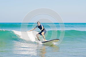 Young man, beginner Surfer learns to surf on a sea foam on the B