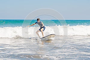 Young man, beginner Surfer learns to surf on a sea foam on the B