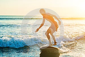 Young man, beginner Surfer learns to surf on a sea foam on the B