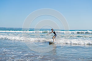 Young man, beginner Surfer learns to surf on a sea foam on the Bali island