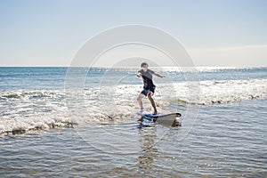 Young man, beginner Surfer learns to surf on a sea foam on the Bali island