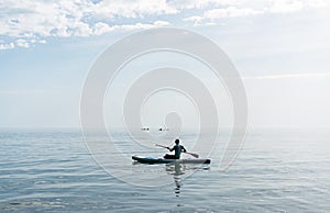 Young man from behind on stand up paddle board on the sea on sunny summer day