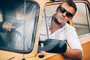 The young man behind the wheel of a beautiful appearance retro car.