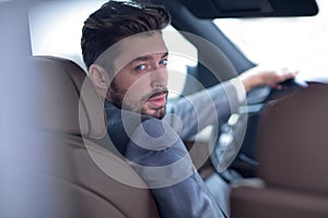 Successful man sitting behind the wheel of a prestigious car