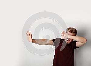 Young man being blinded and covering eyes with hand on background photo