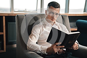 Young man believing in fate reading the Bible on weekend