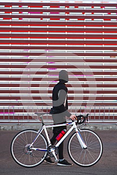 Young man with a bicycle and athletic dress is on an abstract red background
