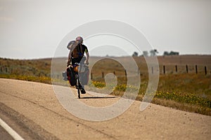 Young man on bicycle at a long journey, rural area