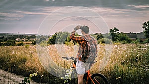 A young man on a bicycle in nature,in the field looks into the distance,a sports guy on a bicycle.