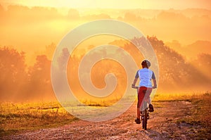 Young man on bicycle ride in beautiful sunrise nature