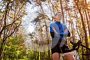 Young man bicyclist riding a road bike in spring forest. Man having rest