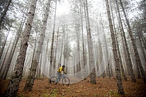 Young man biking through autumn forest