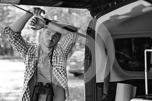 Young man with binoculars near van outdoors,