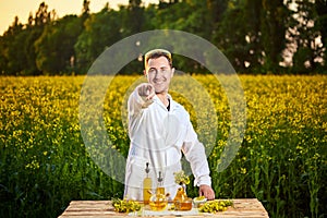 A young man biologist or agronomist examines the quality of rapeseed oil on a rape field. Agribusiness concept