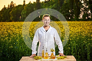 A young man biologist or agronomist examines the quality of rapeseed oil on a rape field. Agribusiness concept