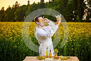 A young man biologist or agronomist examines the quality of rapeseed oil on a rape field. Agribusiness concept