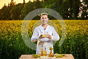 A young man biologist or agronomist examines the quality of rapeseed oil on a rape field. Agribusiness concept