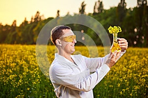 A young man biologist or agronomist examines the quality of rapeseed oil on a rape field. Agribusiness concept